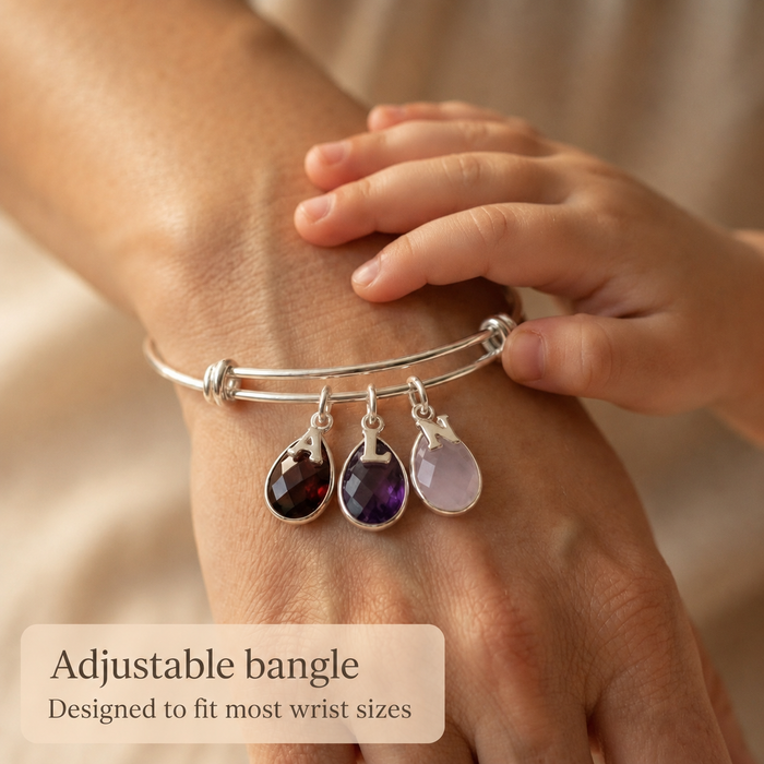 Adjustable bangle bracelet with birthstones and initials shown on wrist.