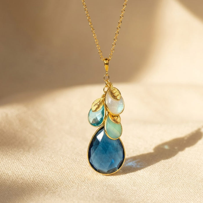 Personalized birthstone necklace for mom or grandma featuring a large teardrop birthstone with smaller family birthstone charms on a gold chain, a meaningful custom jewelry gift.