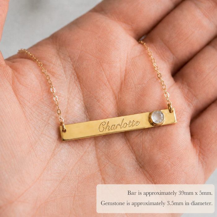 Custom name bar necklace with clear quartz April birthstone shown in hand