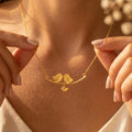 Woman wearing a gold personalized lovebirds family necklace with hand-stamped parent and baby bird initial charms.