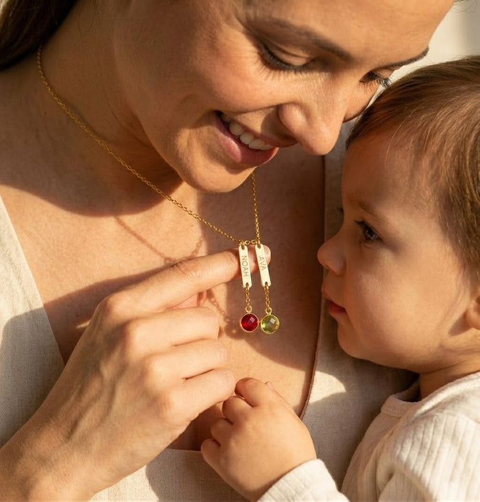 Mother wearing custom engraved name necklace with birthstone charms, personalized family necklace representing children or grandchildren.