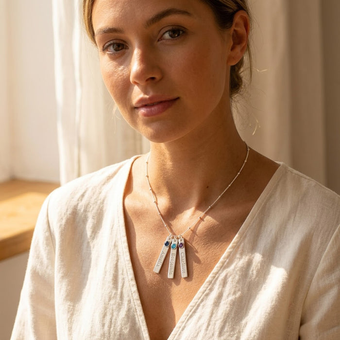 Model wearing custom vertical bar birthstone necklace with engraved name charms