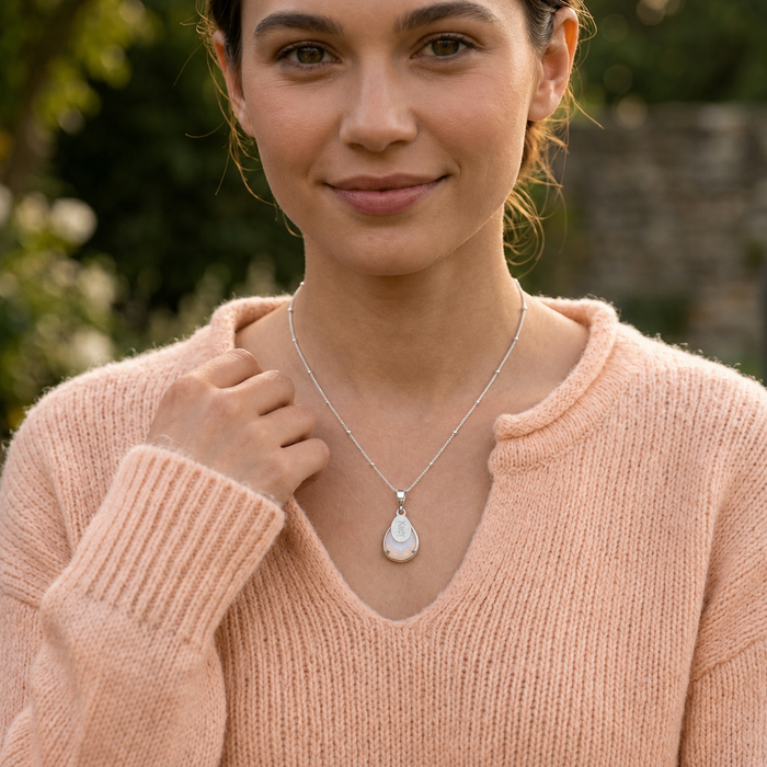 Gold opalite name necklace worn by a model in a peachy color sweater with 16 inch chain length.