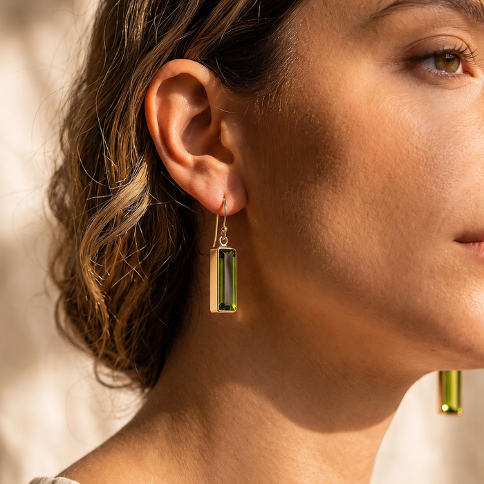Close-up of a model wearing gold peridot baguette earrings