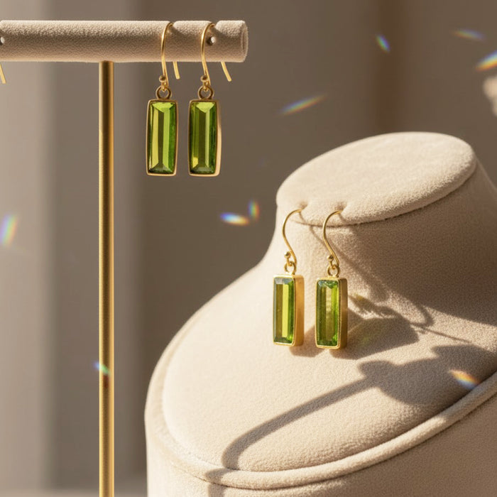 Gold peridot bar earrings displayed on a minimalist jewelry stand