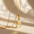 Personalized rainbow moonstone name necklace in gold filled finish with faceted June birthstone pendant and oval name tag.