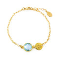 Custom gold filled blue topaz birthstone bracelet with brushed hand stamped initial disk on a white background. december birthstone bracelet, initial bracelet.