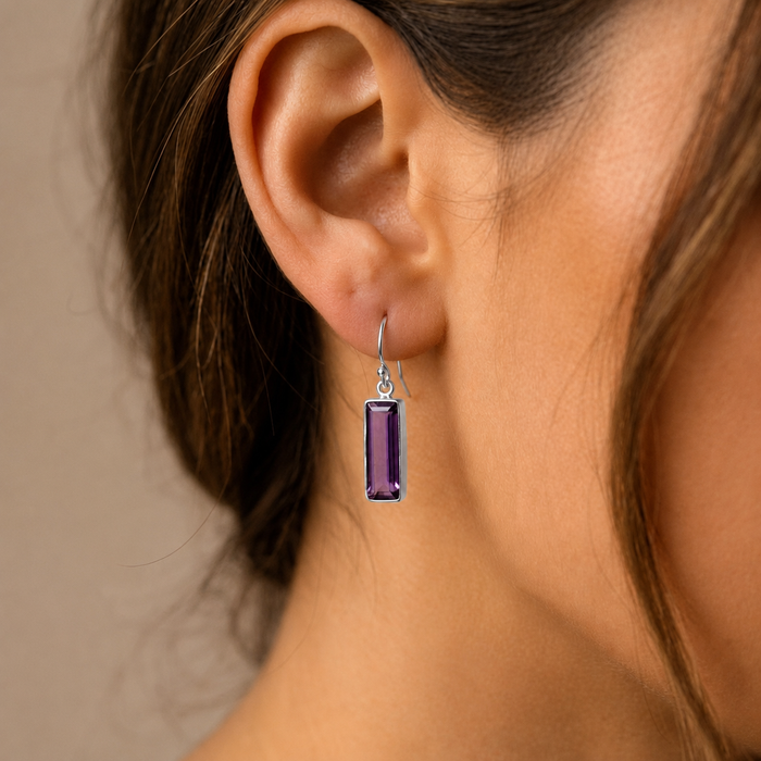 Close-up of purple amethyst baguette earring in gold on model ear