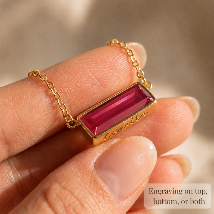 Close-up of personalized ruby quartz baguette necklace with engraving on the side of the gold bar.