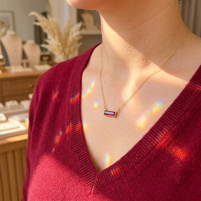 Ruby July birthstone necklace styled on a model wearing a red sweater in natural sunlight.