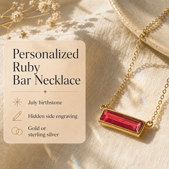 Personalized ruby bar necklace with hidden side engraving shown on cream fabric with product details.