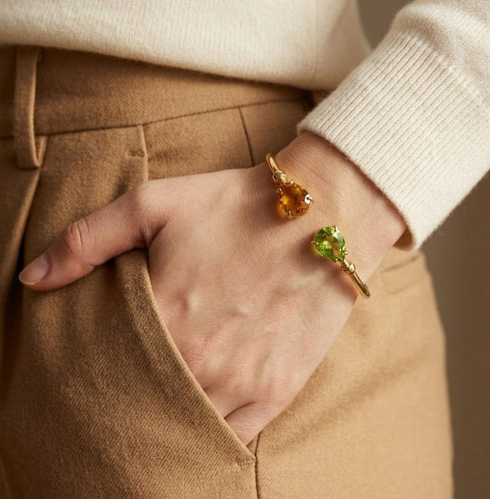 Custom two birthstone bangle bracelet worn on wrist, featuring two pear shaped gemstones chosen to represent loved ones or birth months.