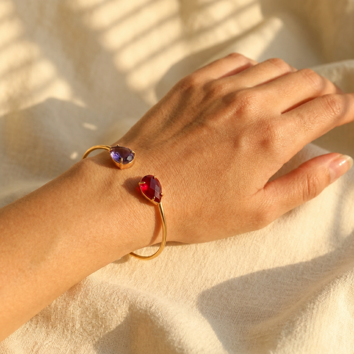 Custom birthstone bangle bracelet worn on hand with two gemstones, designed as personalized jewelry for couples, sisters, moms, or friends.