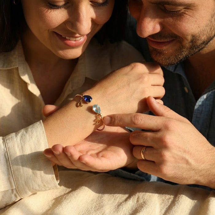 Couple holding hands with personalized birthstone initial bracelet, a romantic anniversary or him and her jewelry gift.