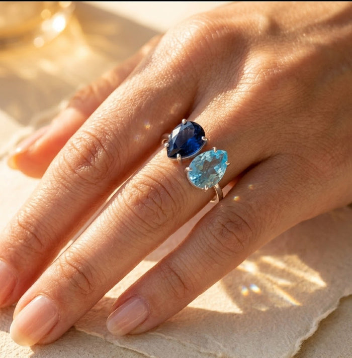 Gold two birthstone ring worn on hand with blue and turquoise teardrop stones